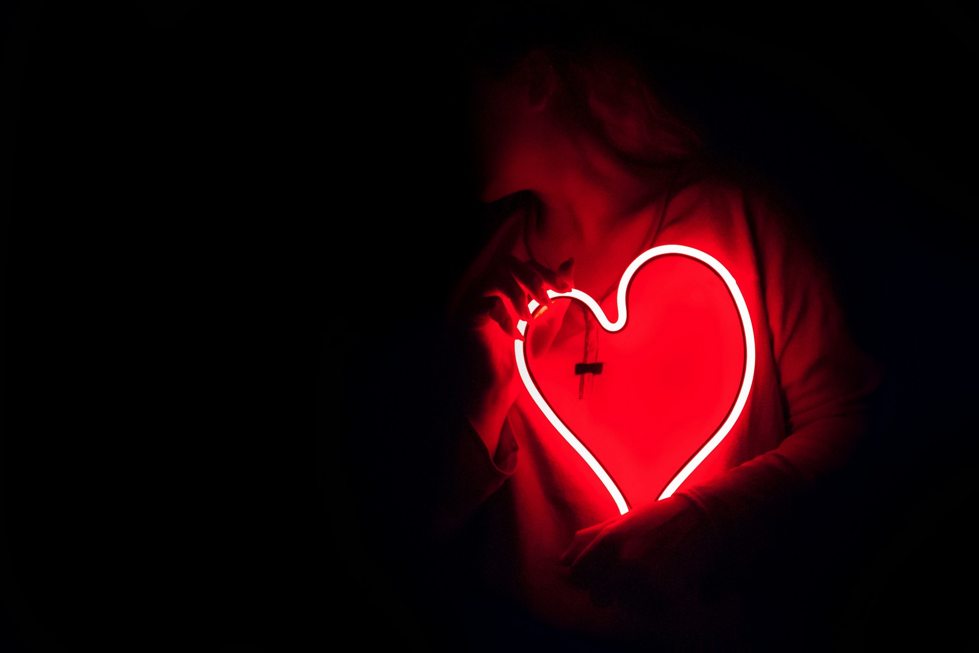 Eine Person hält ein Neonherz in der Hand